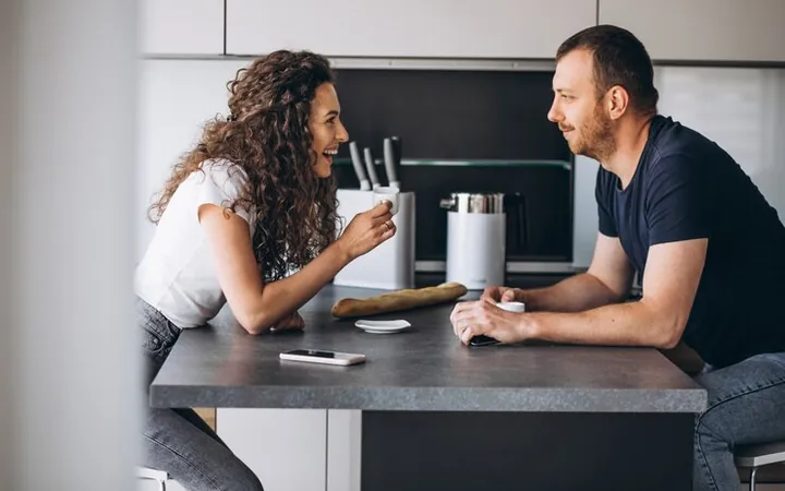 Un bărbat și o femeie stau de vorbă la o cafea, la masa din bucătărie